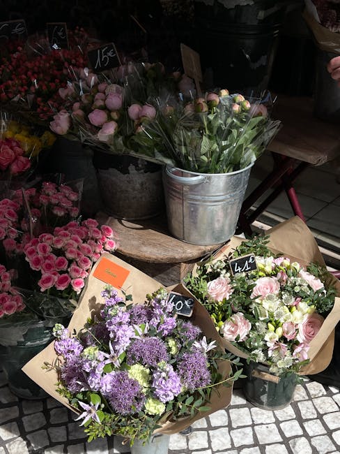 A display of fresh floral arrangements in a flower shop, featuring bouquets and potted plants with various flowers and colors. In the foreground, there are three bouquets: one with purple and lavender